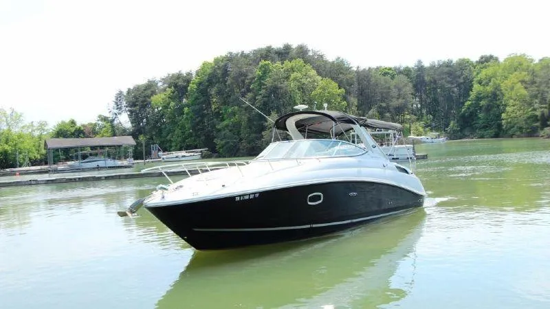 Slide: The Image of 2009 Sea Ray 270 Sundancer boat on a calm lake with lush green trees. - 3