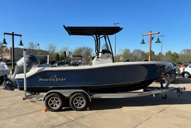 The Image of 2022 NauticStar 2102 Legacy boat on trailer, parked outdoors under clear blue sky. - 1