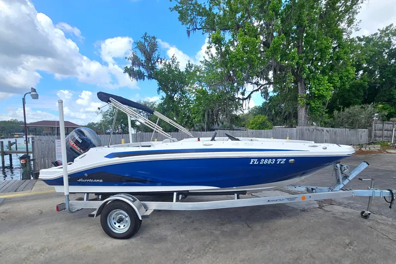 Slide: The Image of 2023 Hurricane SunDeck Sport 188 OB boat on trailer, parked near a dock. - 1