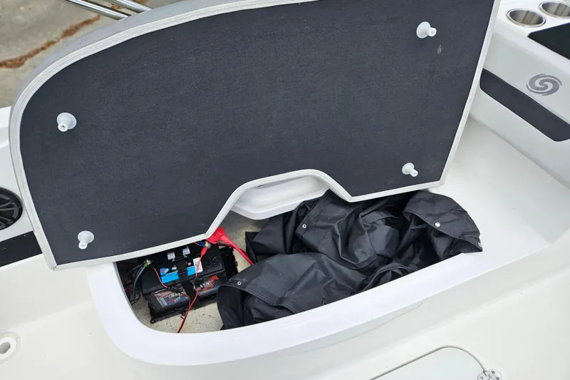 Slide: The Image of Open storage compartment in 2023 Hurricane SunDeck Sport 188 OB boat, revealing battery and cover. - 13
