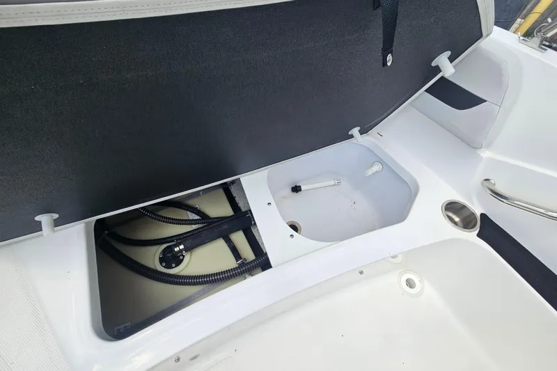 Slide: The Image of 2023 Hurricane SunDeck Sport 188 OB boat storage compartment with open hatch and visible hoses. - 15