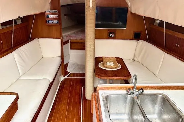 Slide: The Image of Interior of a 1992 Catalina 34 sailboat with cozy seating and a compact kitchen area. - 10
