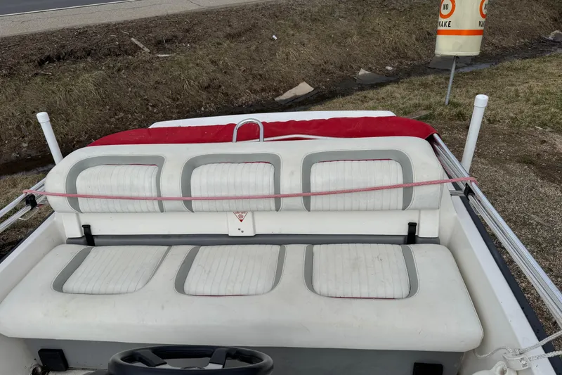 Slide: The Image of 1997 Boston Whaler Rage 15 boat interior with white cushioned seats and red cover. - 8