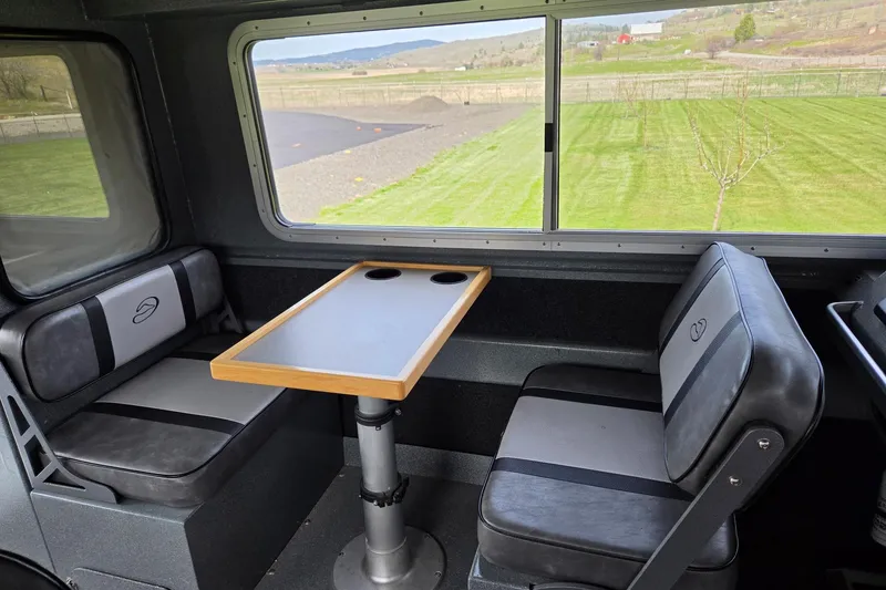 Slide: The Image of Interior of a 2012 Duckworth 28 Offshore boat with seating and table, overlooking grassy landscape. - 13