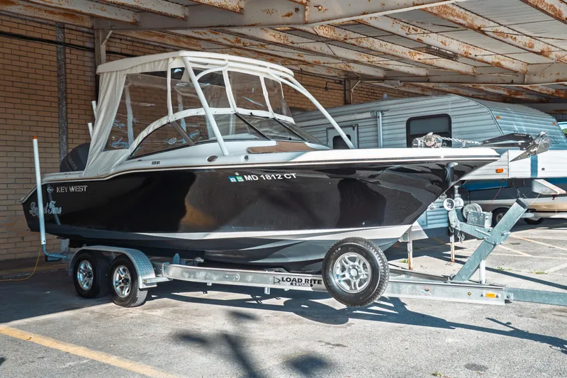 The Image of 2019 Key West 239 DFS boat on trailer, parked under a metal roof. - 0