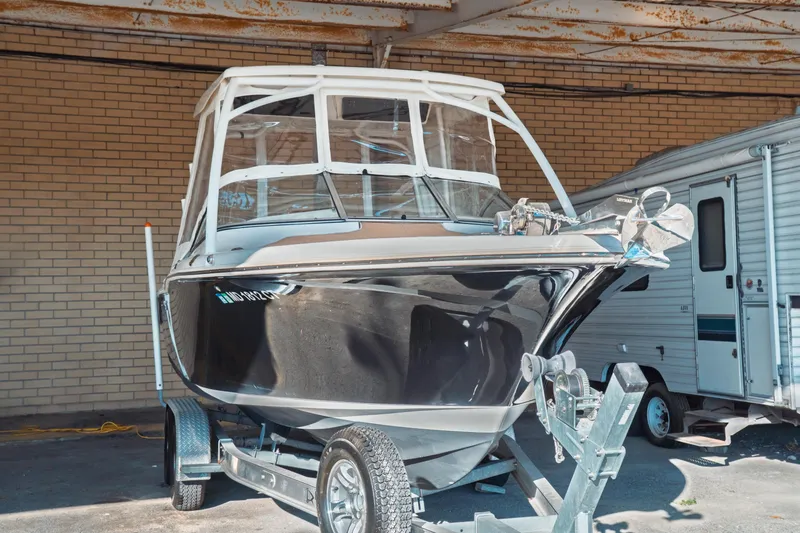 Slide: The Image of 2019 Key West 239 DFS boat on trailer, parked indoors near a brick wall. - 2