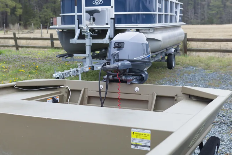 Slide: The Image of 2025 G3 Gator Tough 1652 VBW boat with outboard motor, parked near a trailer. - 6