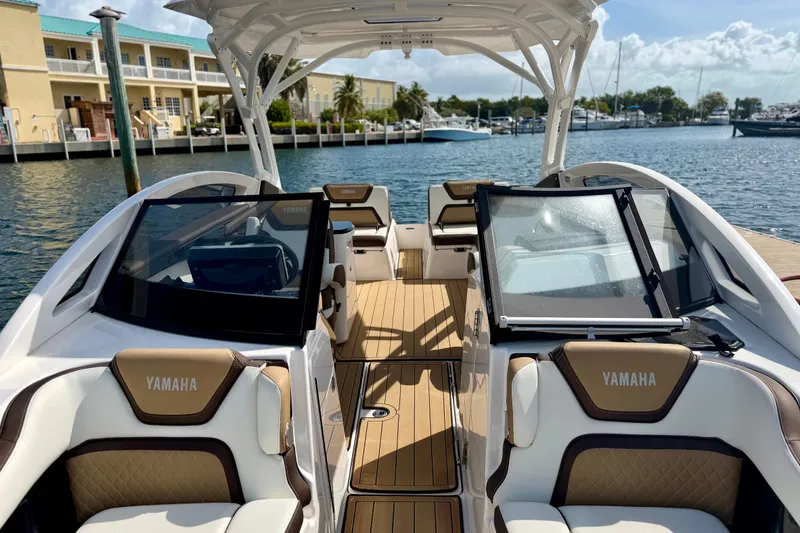 Slide: The Image of 2022 Yamaha Boats 275SD interior with luxurious seating and sleek design at a marina. - 12