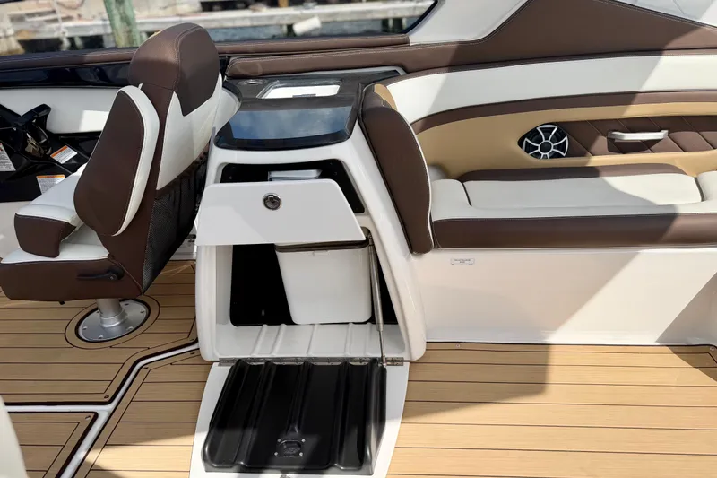 Slide: The Image of 2022 Yamaha Boats 275SD interior with brown and white seating, open storage compartment. - 28