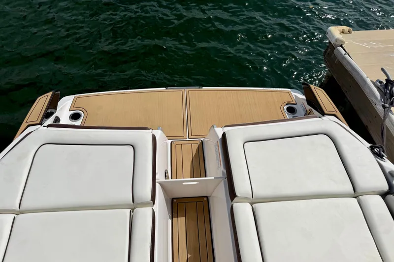 Slide: The Image of 2022 Yamaha Boats 275SD swim platform with cushioned seating, docked by the water. - 33