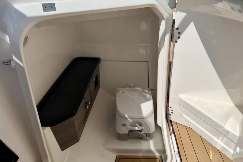 Slide: The Image of 2022 Yamaha Boats 275SD interior bathroom with compact toilet and storage cabinet. - 36