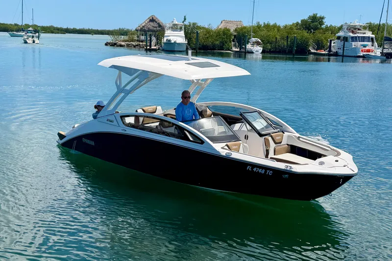 Slide: The Image of 2022 Yamaha Boats 275SD cruising on a serene waterway with lush greenery. - 5