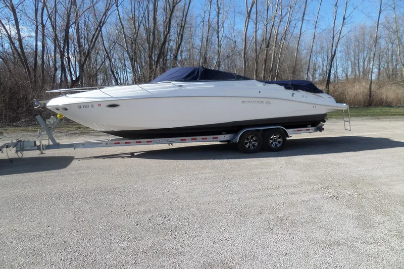 The Image of 2013 Rinker 296 Captiva Cuddy boat on trailer, parked outdoors. - 1