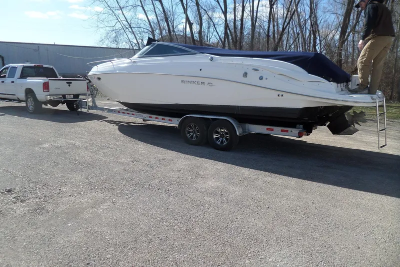 Slide: The Image of 2013 Rinker 296 Captiva Cuddy boat on trailer, hitched to a white truck. - 2