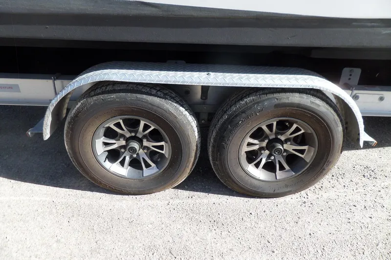 Slide: The Image of Trailer wheels of a 2013 Rinker 296 Captiva Cuddy boat on a gravel surface. - 8