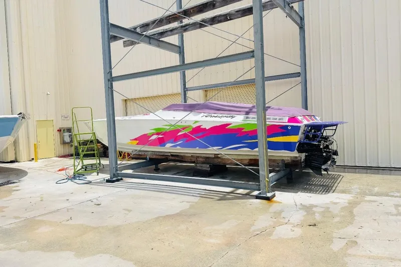 The Image of 1997 Powerplay Powerboats 33 Sport Deck with vibrant graphics, stored on a metal rack. - 0