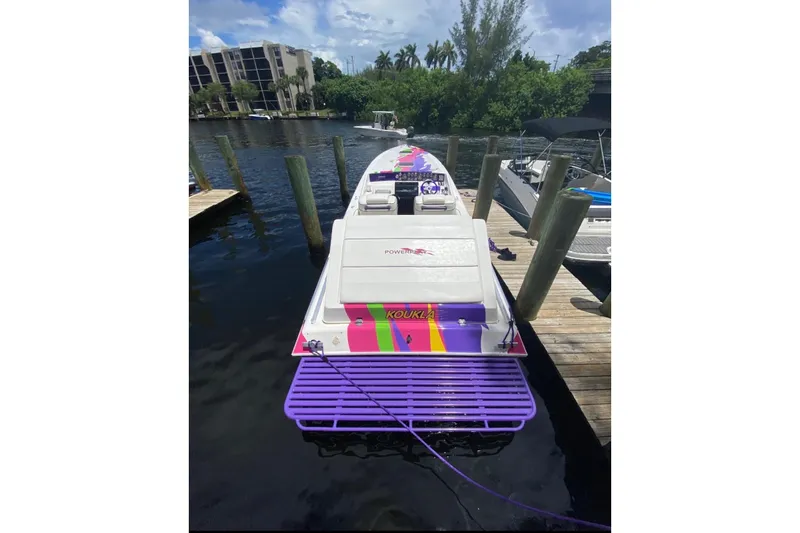 Slide: The Image of 1997 Powerplay Powerboats 33 Sport Deck moored at a dock, featuring vibrant purple and pink accents. - 2