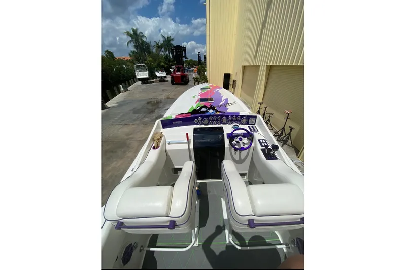 Slide: The Image of 1997 Powerplay Powerboats 33 Sport Deck with vibrant dashboard and seating, docked outdoors. - 3
