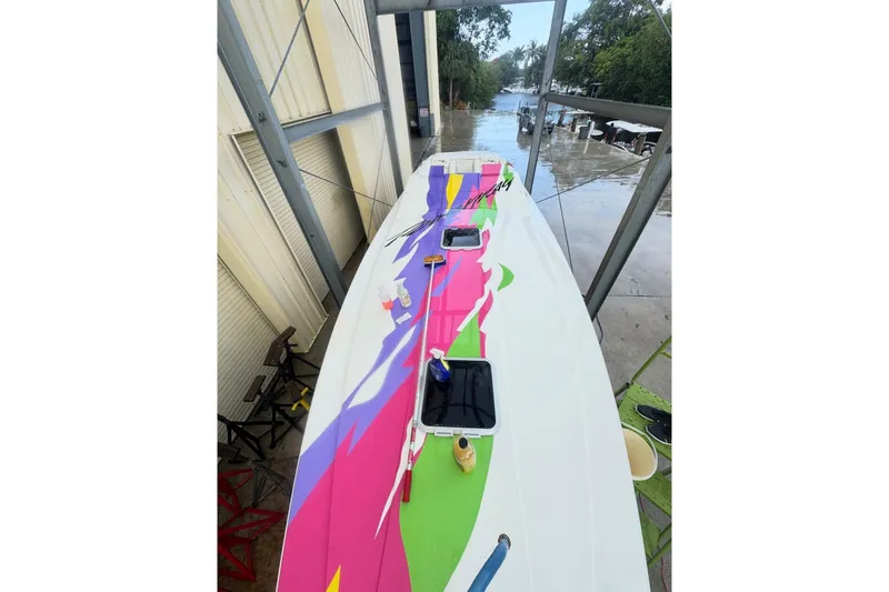 Slide: The Image of 1997 Powerplay Powerboats 33 Sport Deck with vibrant, colorful design docked near water. - 5