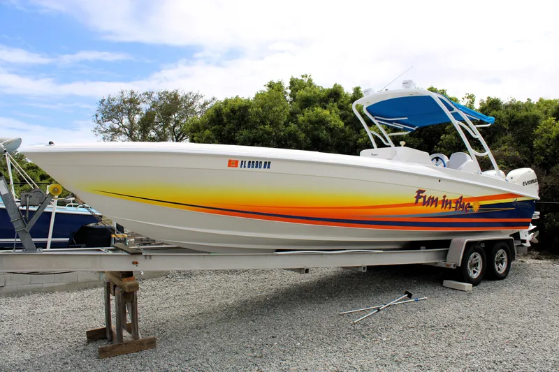 The Image of 2007 Renegade 29CC boat on trailer with vibrant graphics and blue canopy. - 0