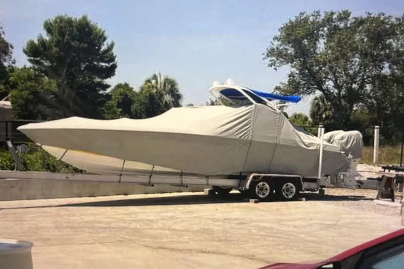 Slide: The Image of Covered 2007 Renegade 29CC boat on trailer, parked outdoors with trees in background. - 2