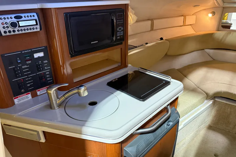 Slide: The Image of 2009 Sea Ray 240 Sundancer cabin with kitchenette, sink, microwave, and seating area. - 20