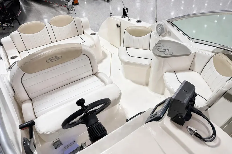 Slide: The Image of 2009 Sea Ray 240 Sundancer boat interior with white seating and steering wheel. - 28