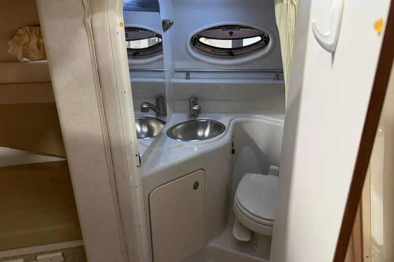 Slide: The Image of 2009 Sea Ray 240 Sundancer boat bathroom with sink, toilet, and porthole window. - 19
