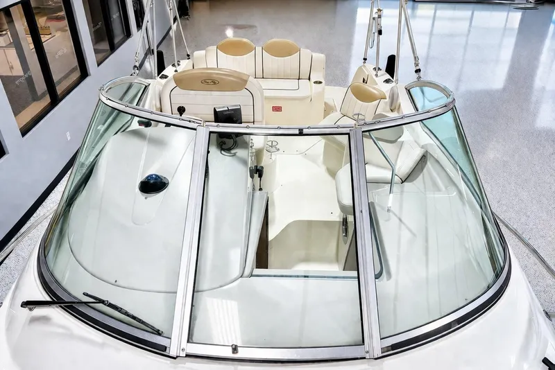Slide: The Image of 2009 Sea Ray 240 Sundancer boat interior with beige seating and sleek windshield design. - 3