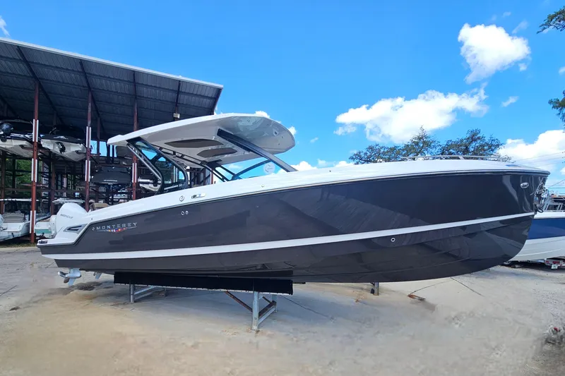 The Image of 2026 Monterey Elite 30 OB boat displayed outdoors under a clear blue sky. - 0