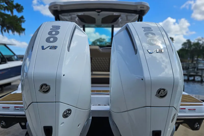 Slide: The Image of Twin 300 V8 engines on a 2026 Monterey Elite 30 OB boat, docked under a blue sky. - 2