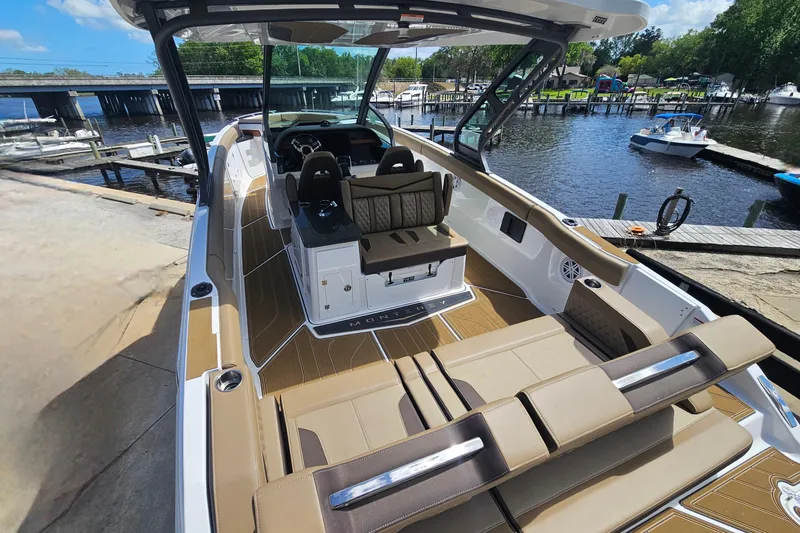 Slide: The Image of 2026 Monterey Elite 30 OB boat interior with luxurious seating, docked by a scenic waterfront. - 3