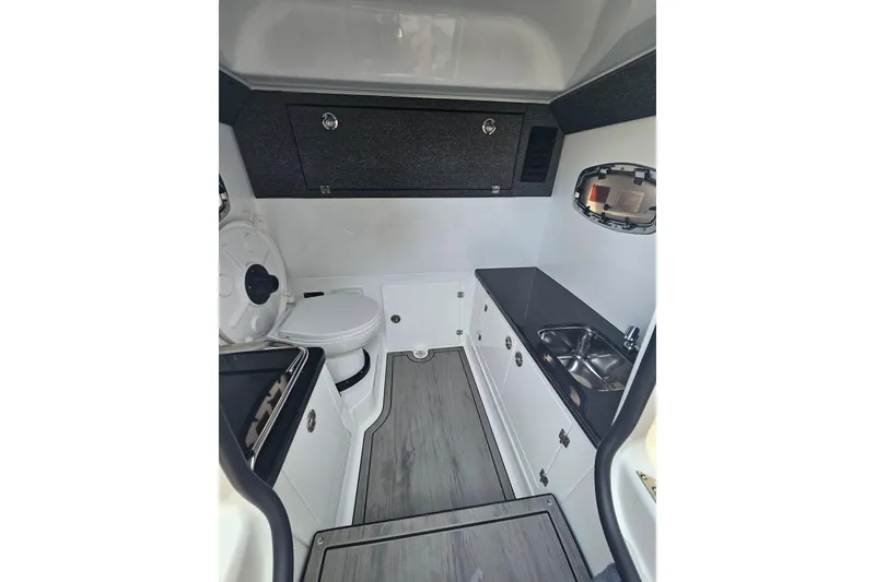 Slide: The Image of Interior of 2026 Monterey Elite 30 OB boat featuring compact kitchenette and toilet. - 31