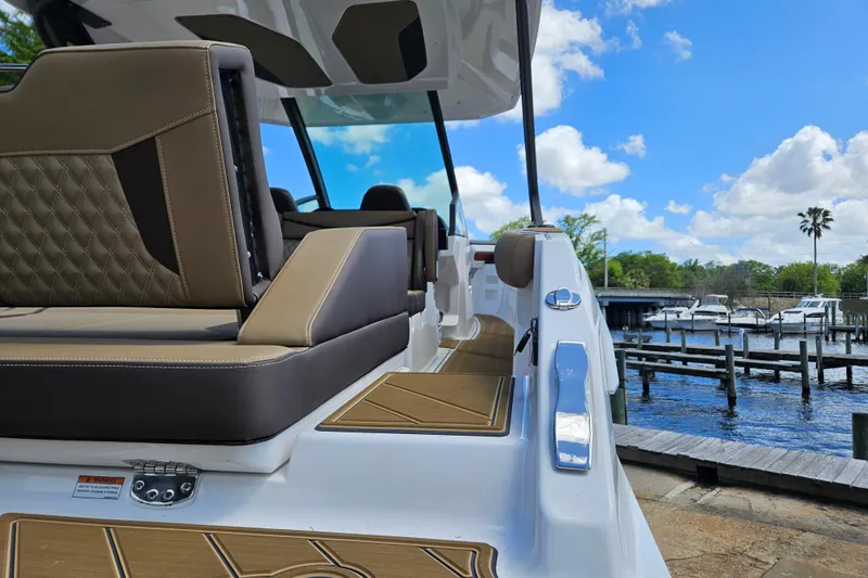 Slide: The Image of 2026 Monterey Elite 30 OB boat interior with luxurious seating, docked by a scenic marina. - 8