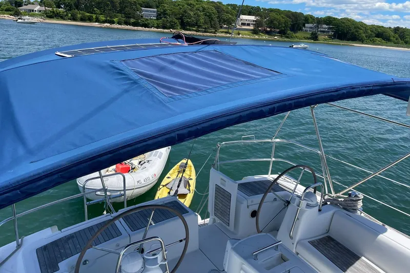 Slide: The Image of 2007 Beneteau Oceanis 46 sailboat with blue canopy, docked near a scenic shoreline. - 43
