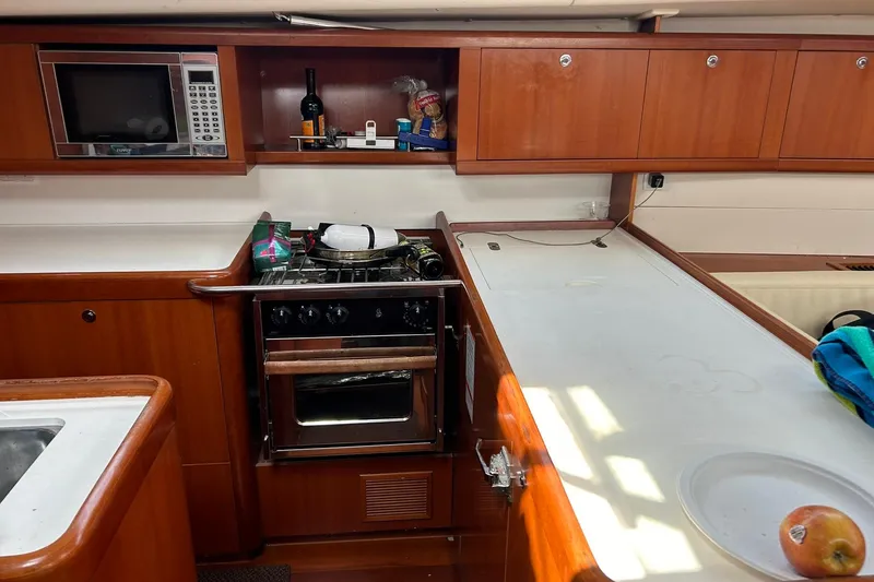 Slide: The Image of Galley of 2007 Beneteau Oceanis 46 yacht with stove, microwave, and wooden cabinetry. - 8