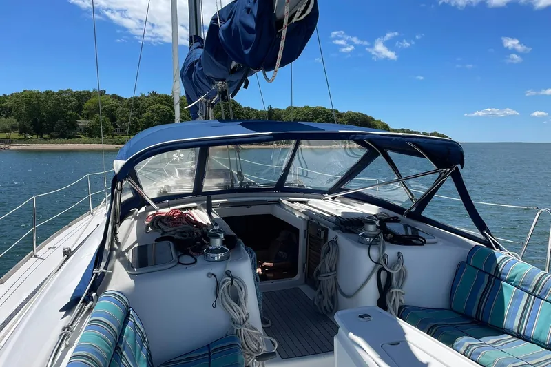 Slide: The Image of 2007 Beneteau Oceanis 46 sailboat cockpit with blue canopy, moored near lush shoreline. - 41