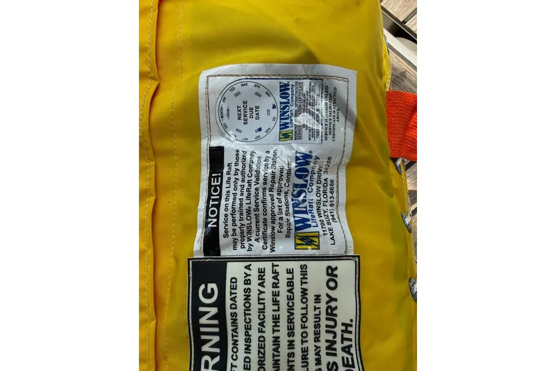 Slide: The Image of Yellow Winslow life raft label with service instructions and warning text. Jeanneau 51, 2018. - 31