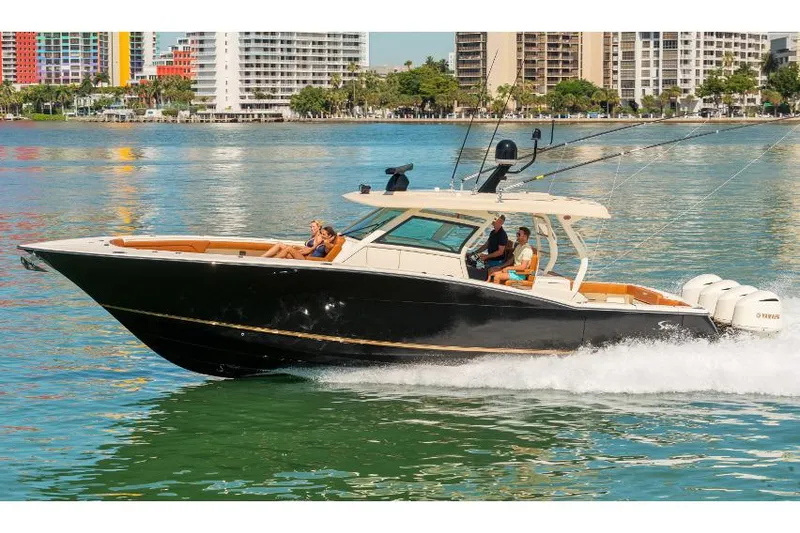 Slide: The Image of Manufacturer Provided Image: 2017 Scout 420 LXF boat cruising on water near city buildings. - 2