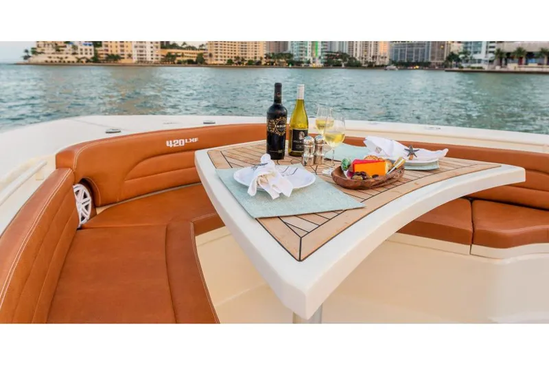 Slide: The Image of Manufacturer Provided Image: 2017 Scout 420 LXF boat with a dining setup on deck, overlooking the water. - 3