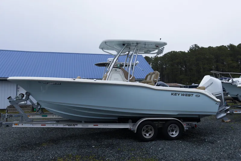 The Image of 2020 Key West 239 FS boat on trailer, parked outdoors near blue-roofed building. - 1