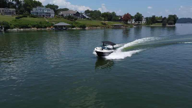 Slide: The Image of 2023 Sea Ray SLX 260 Surf boat cruising on a scenic lake near waterfront homes. - 11