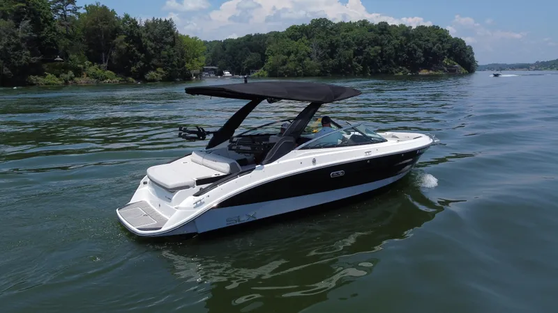 Slide: The Image of 2023 Sea Ray SLX 260 Surf boat cruising on a scenic lake. - 13