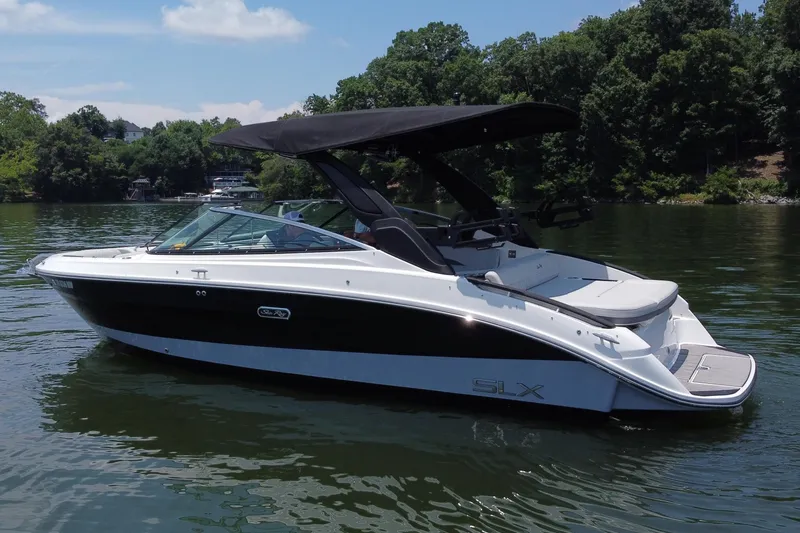 Slide: The Image of 2023 Sea Ray SLX 260 Surf boat on a calm lake with lush green trees. - 3