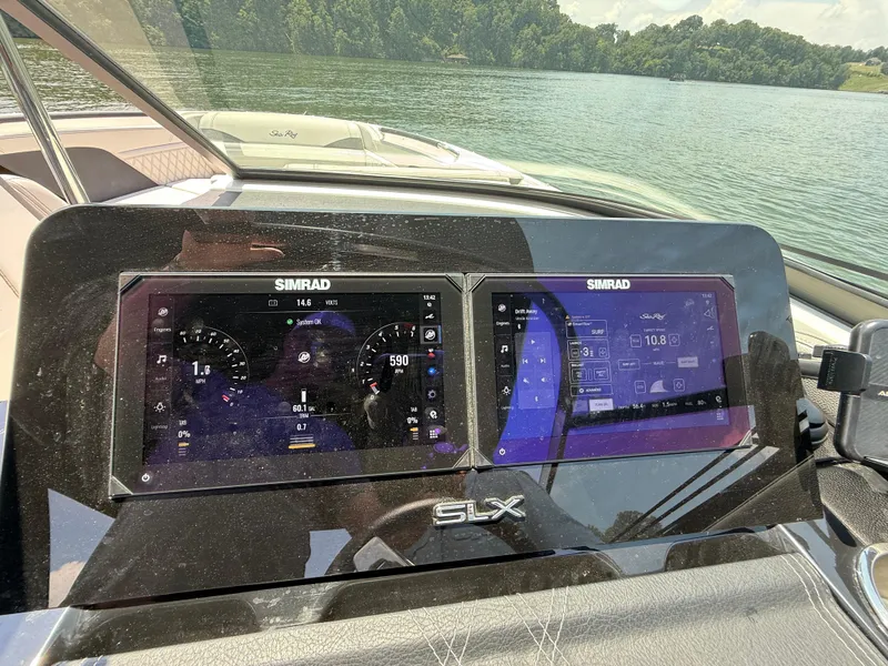 Slide: The Image of 2023 Sea Ray SLX 260 Surf dashboard with Simrad displays on a lake. - 30