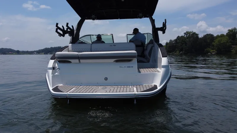 Slide: The Image of 2023 Sea Ray SLX 260 Surf boat on calm water, rear view with passengers. - 4