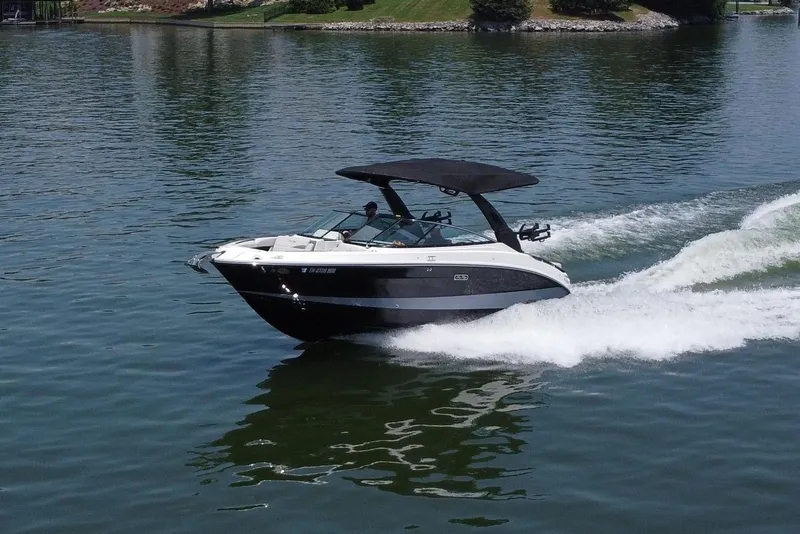 Slide: The Image of 2023 Sea Ray SLX 260 Surf boat cruising on a serene lake with scenic background. - 9