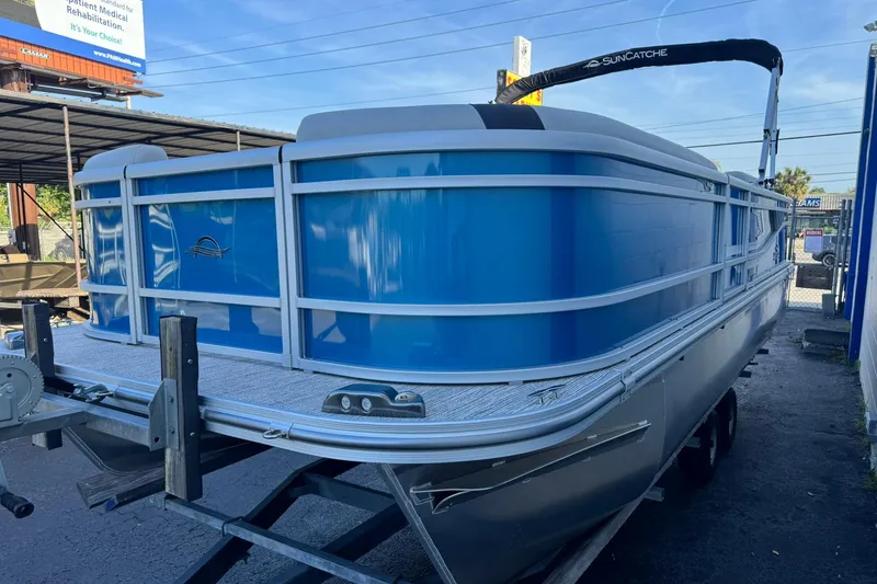 Slide: The Image of 2026 SunCatcher Select 22RF pontoon boat in blue, parked on a trailer. - 10