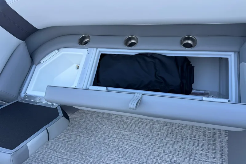 Slide: The Image of SunCatcher Select 22RF 2026 boat interior storage compartment with gray seating and cup holders. - 17