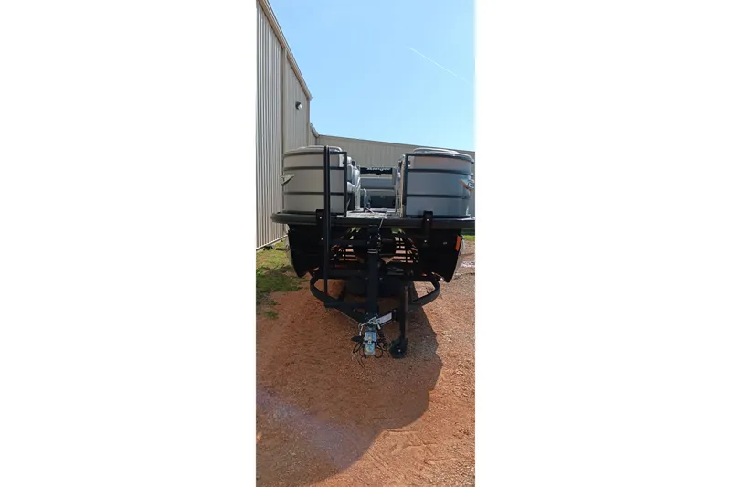 Slide: The Image of 2023 Ranger 2500LS pontoon boat on trailer, parked beside a metal building. - 20